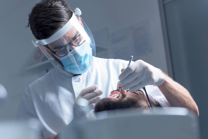 Zahnarzt bei Behandlung mit Schutzausrüstung